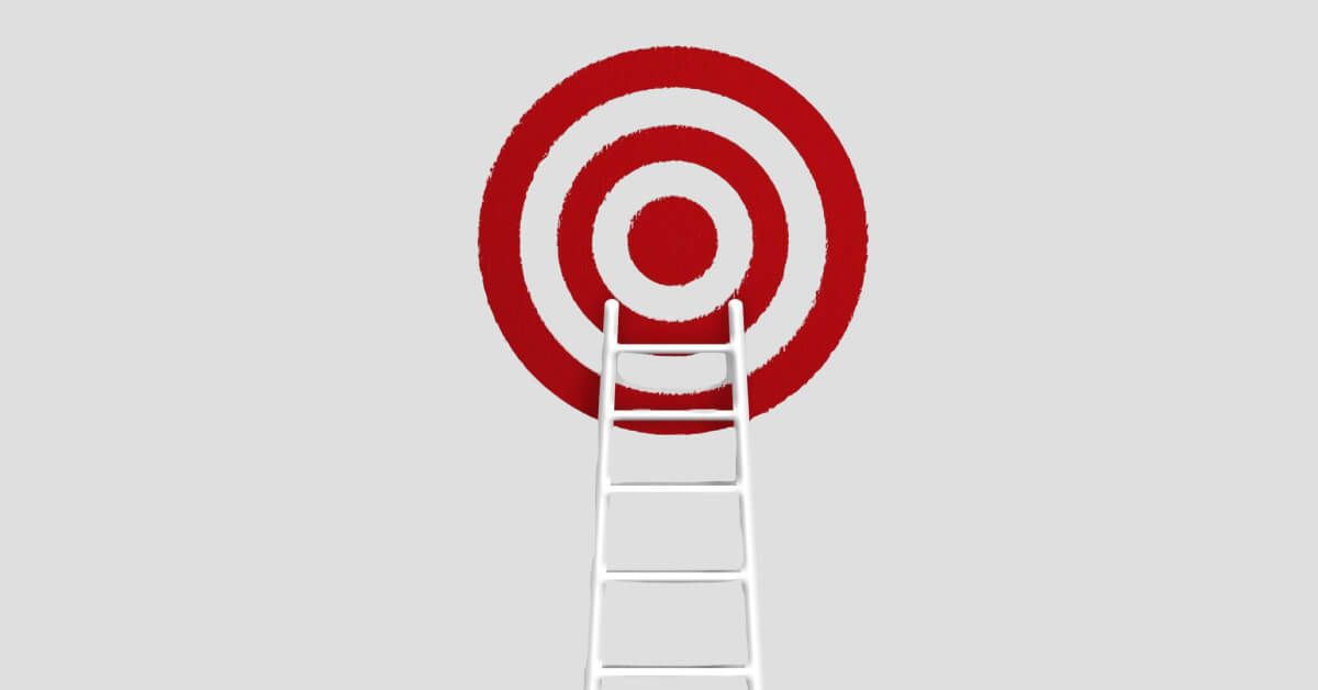 A white ladder leading up to a red and white target board