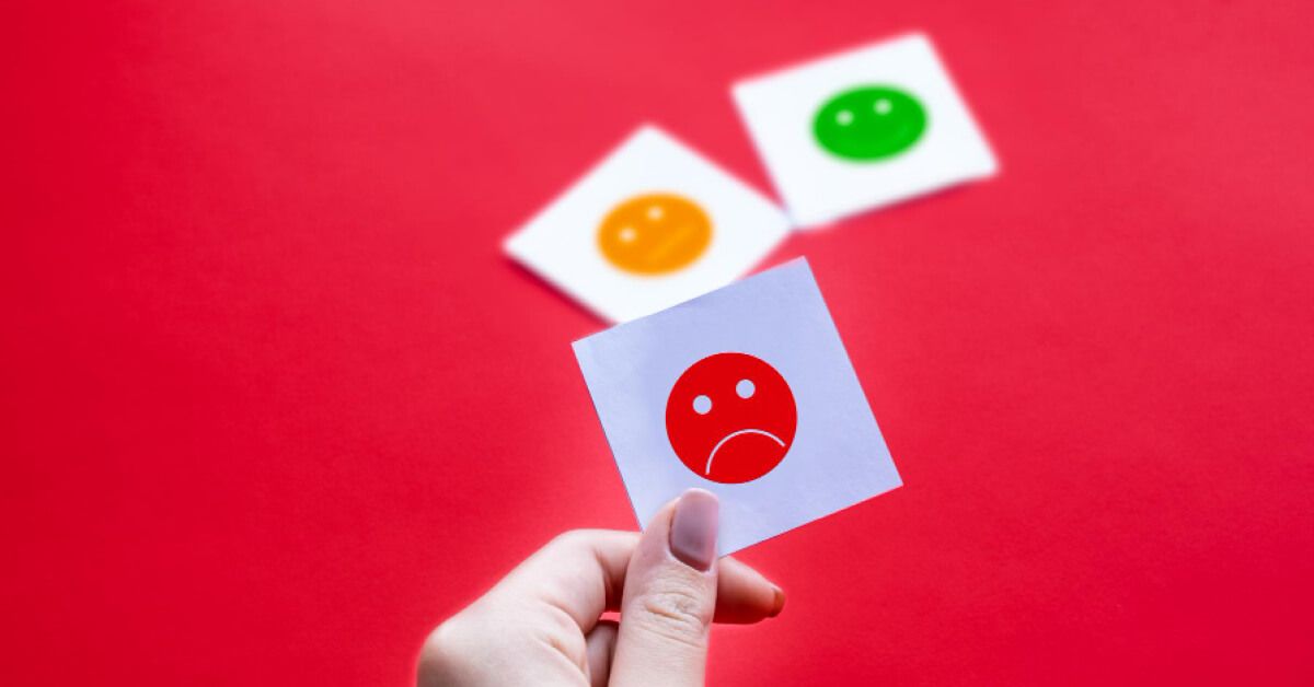 Person holding a emoji review card against a red backdrop