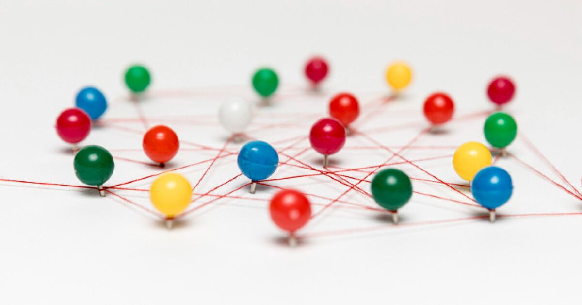 A network of multicolored bobby pins connected by a red string