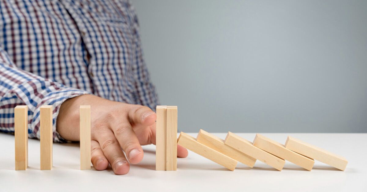 Person blocking a series of wooden blocks from falling over