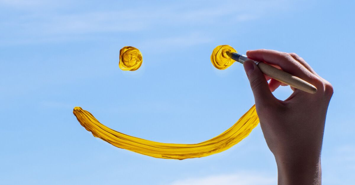 Person using a brush to paint a smiley face