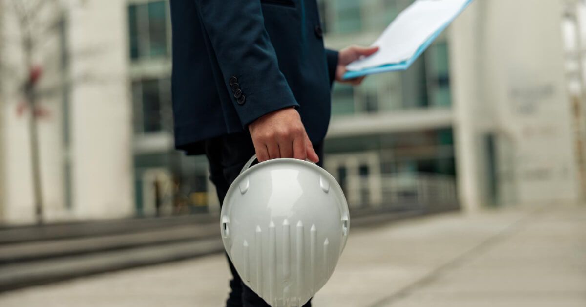 Business person holding a hard hat and a checklist