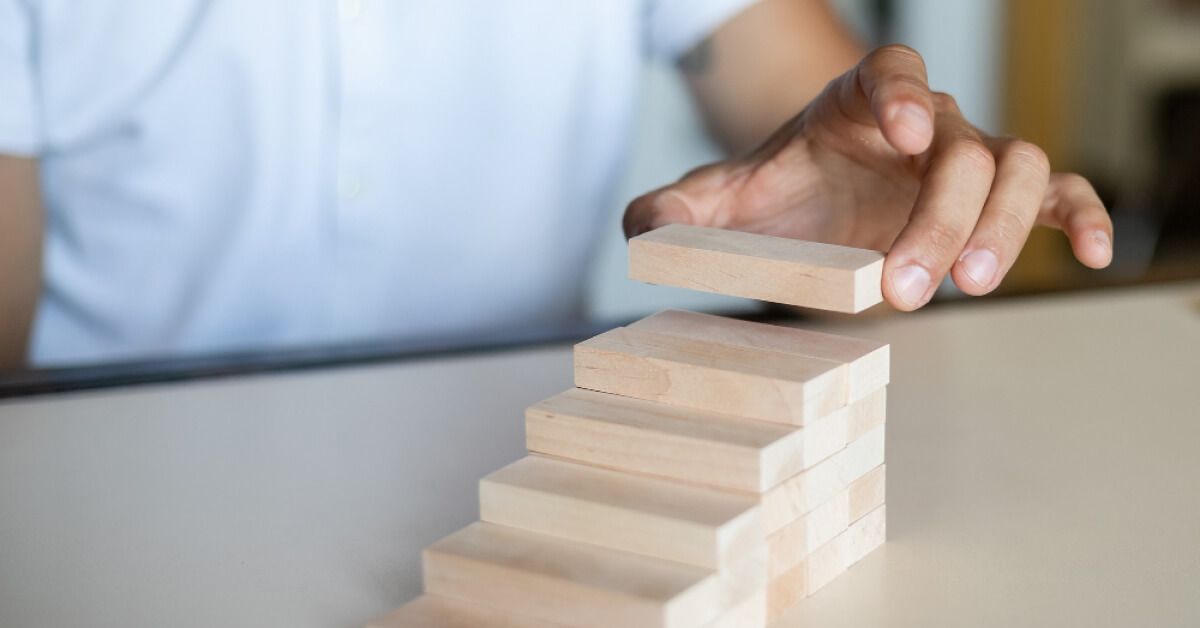 Person arranging a wooden block on a set of wooden blocks arranged in a stepwise manner