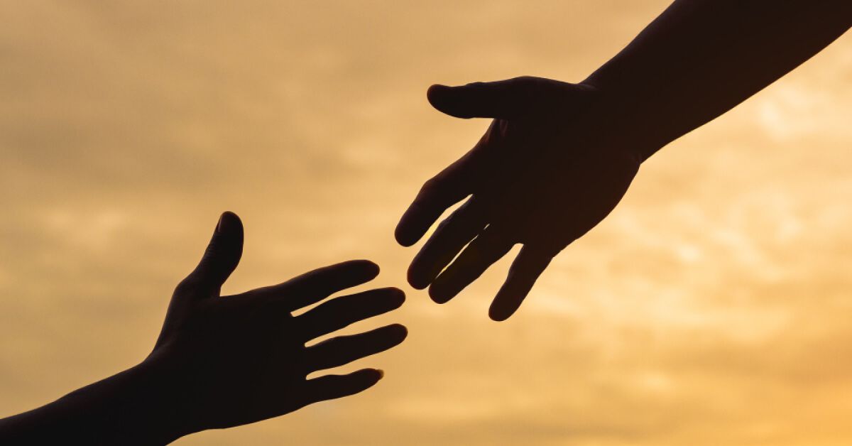 Silhouette of two people reaching out to each other