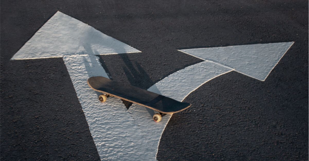 A skateboard on top of two diverging arrows