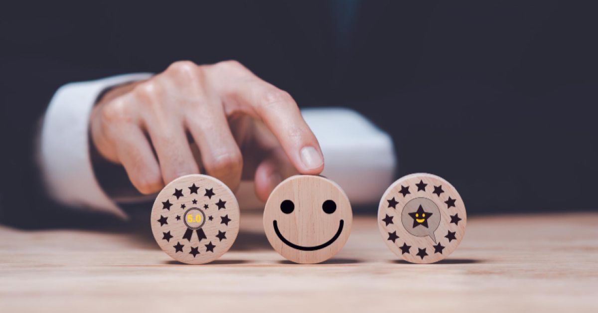 Person holding a wooden block with a smiley face, surrounded by two other blocks with rating visuals