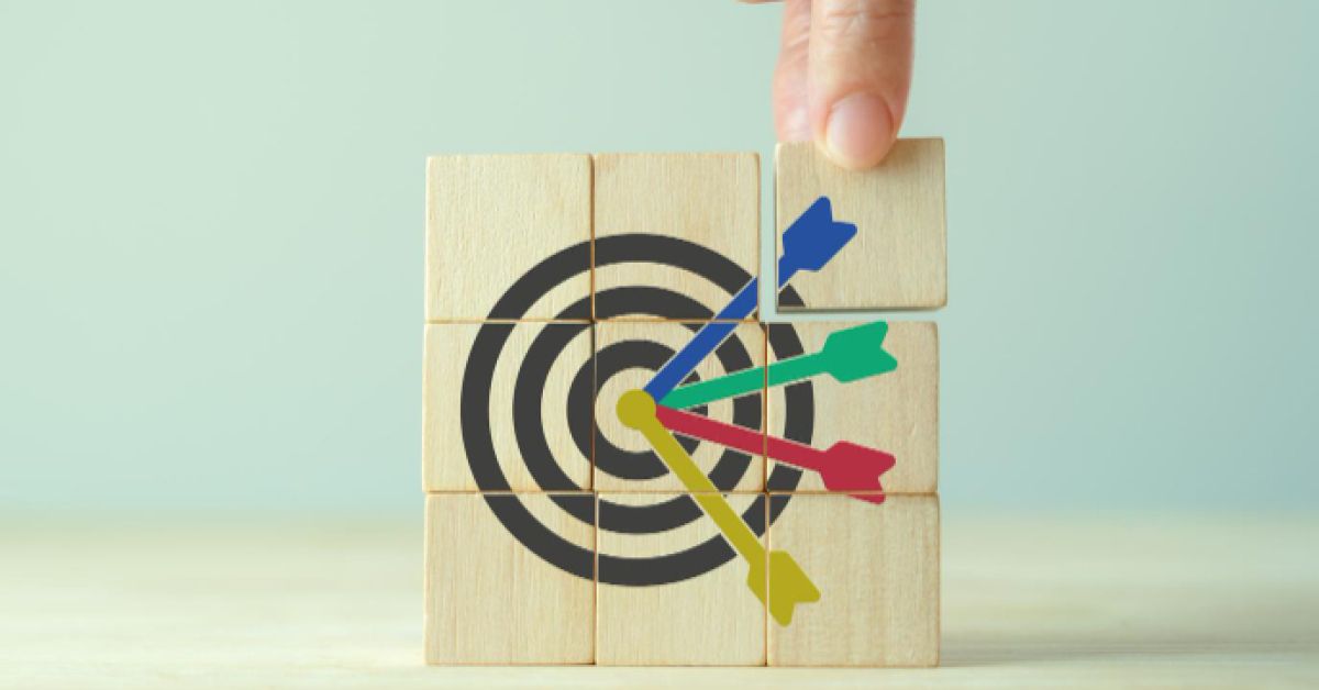 Person removing a wooden chip from a group of other chips that form a multicolored dartboard