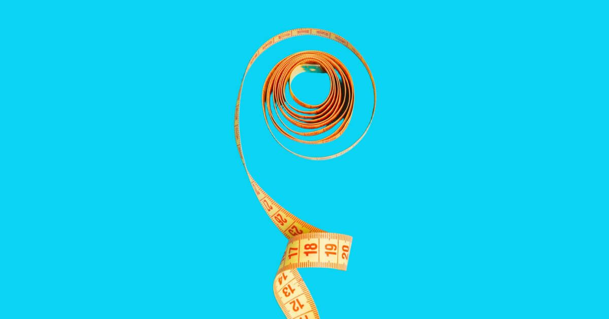 A measuring tape rolled out against a blue backdrop