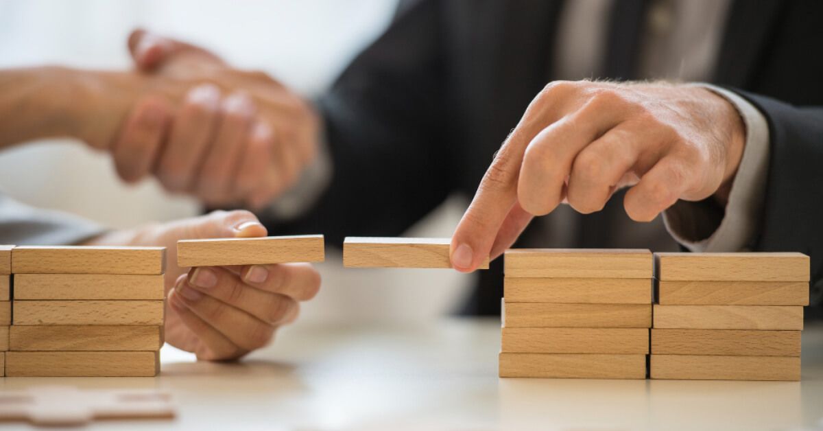 Two people connecting groups of wooden blocks