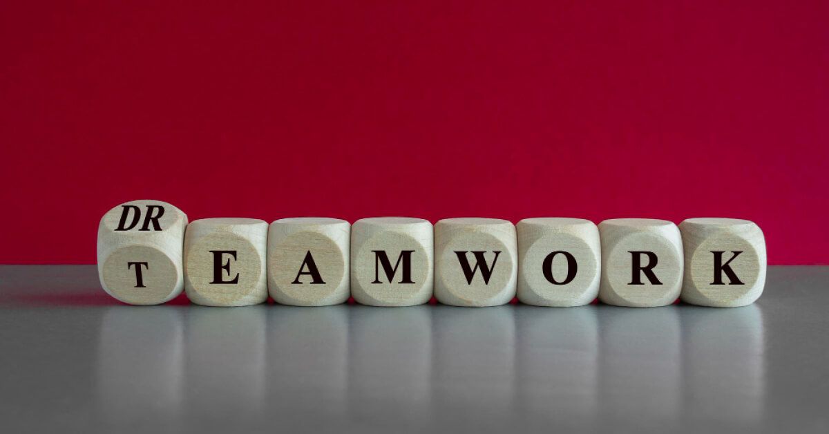 A series of wooden dice with letters on them spelling the word "teamwork"