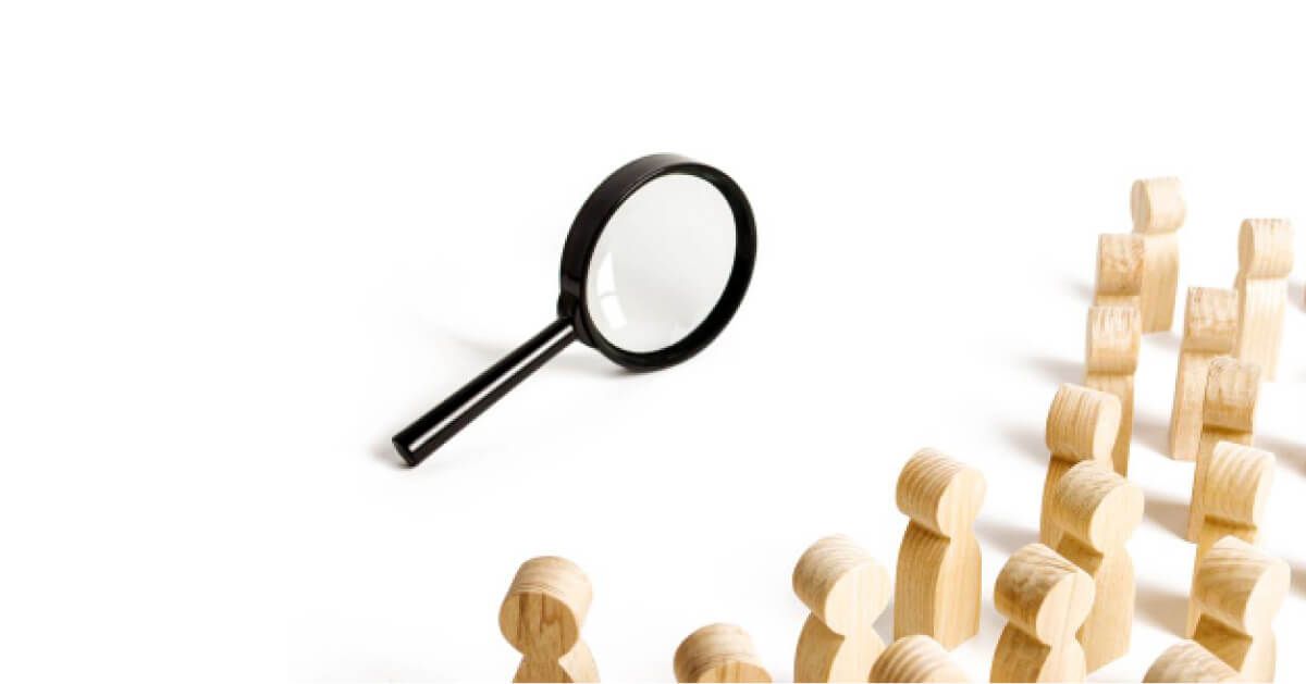 A magnifying glass looking at wooden pawns