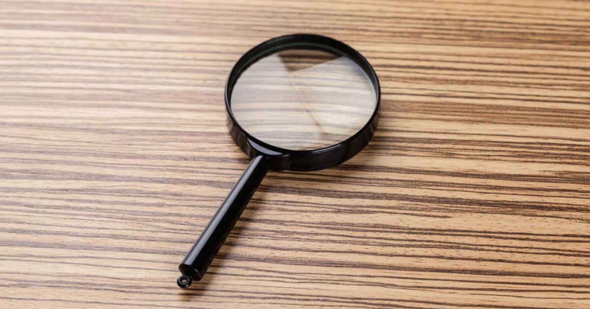 A magnifying glass laid flat on a wooden board