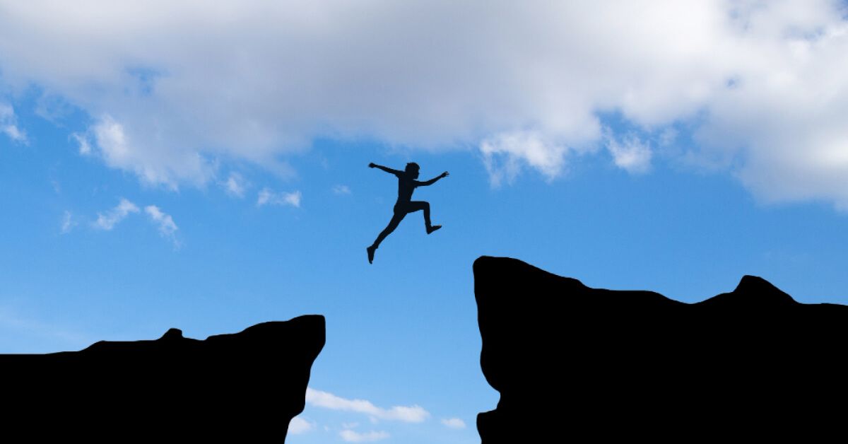 A man jumping from one cliff to reach other cliff