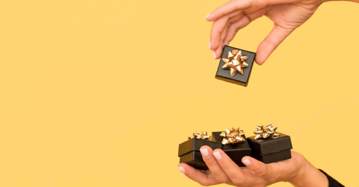 Person holding a group of black boxes with golden stars on them