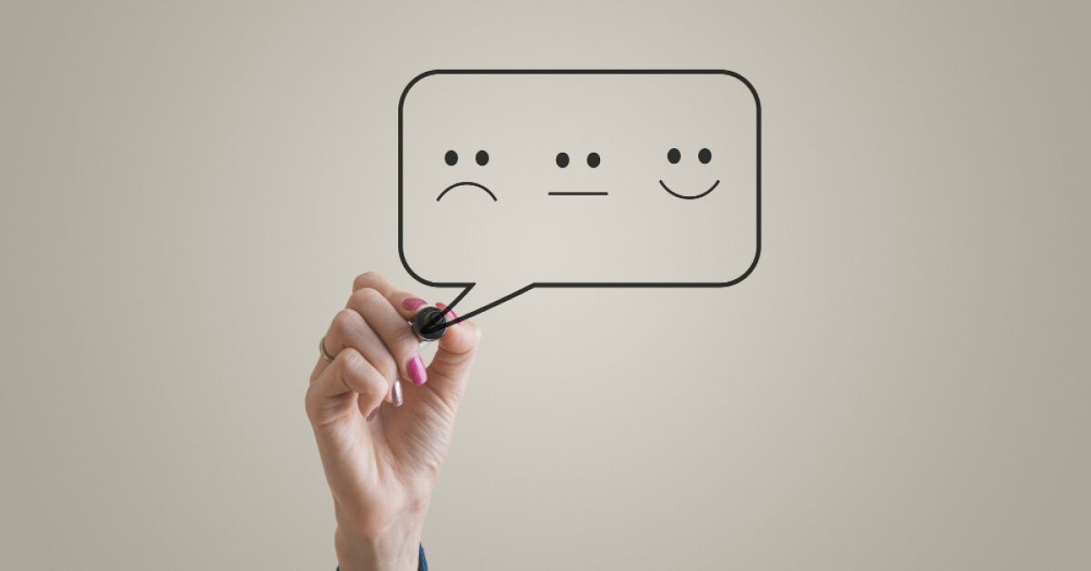 Person drawing a dialogue box with different emoticons