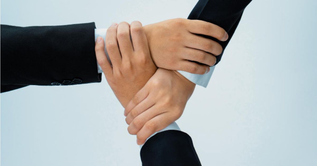 Three employees interlocking their hands in solidarity