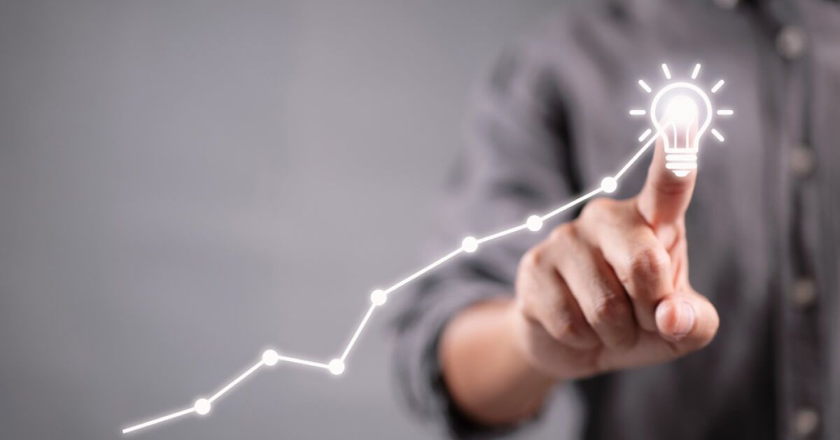 Person pointing finger at an upward moving line graph with a lightbulb