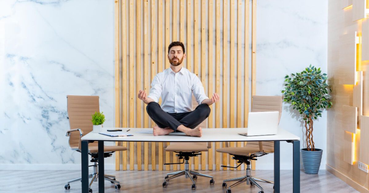 Employee sitting in a meditative pose on top of a table