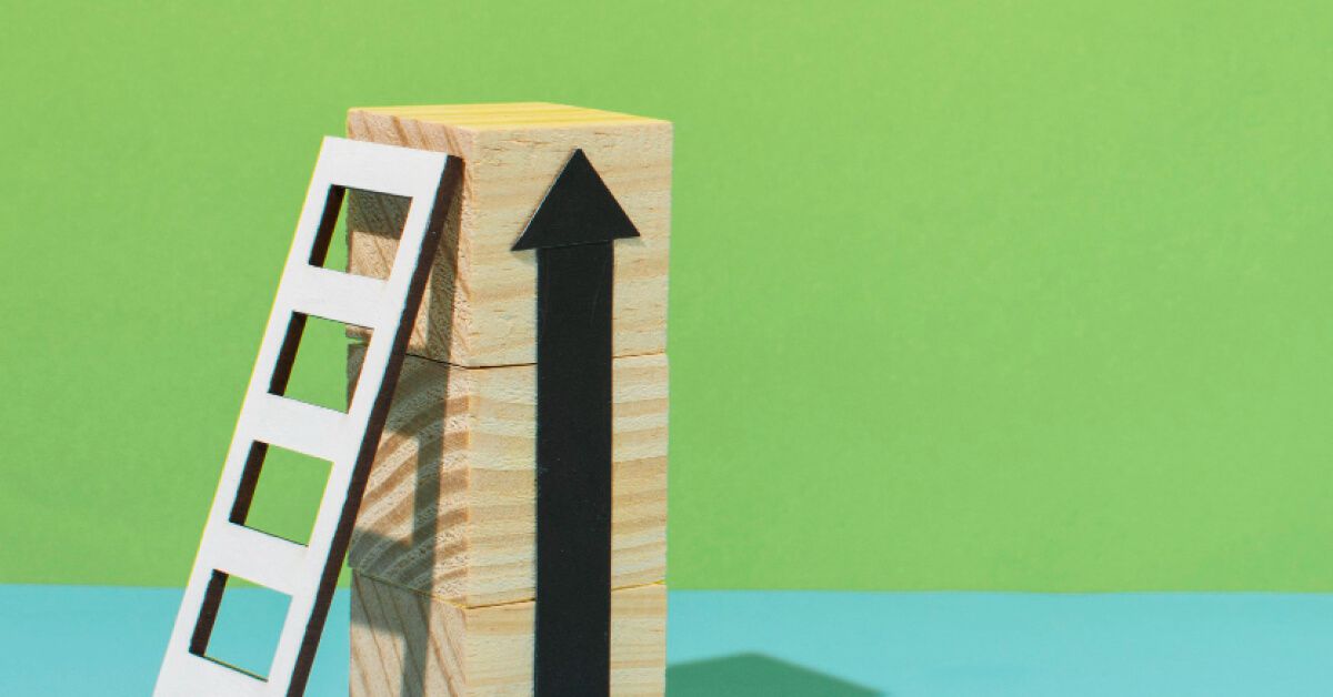 A white ladder against a stack of wooden blocks with a black arrow