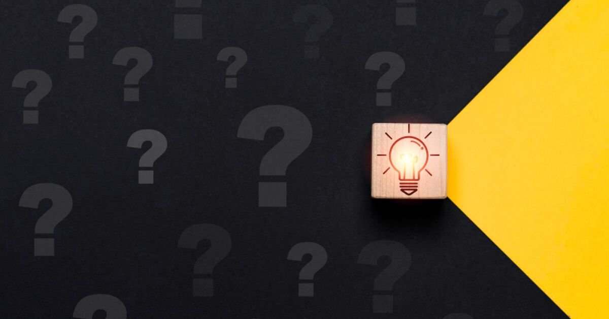 A wooden block with an illuminated bulb visual, surrounded by question marks