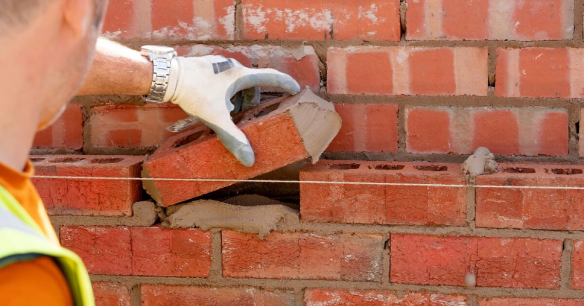 Mason laying down a brick with mortar