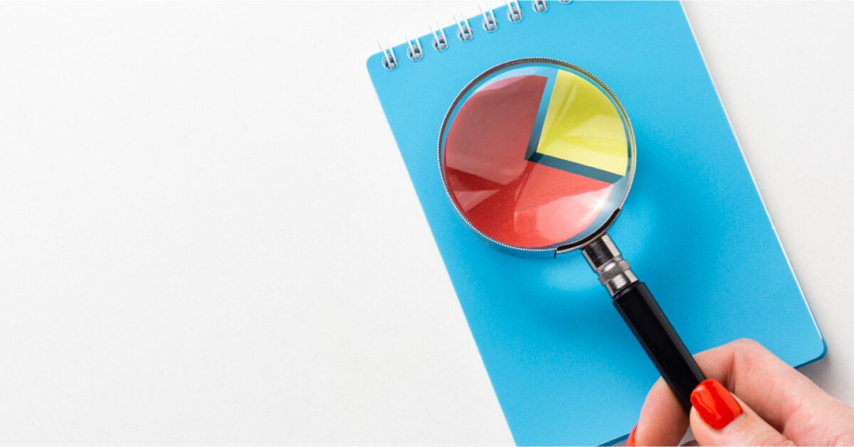 Magnifier glass held over a pie chart on a notebook