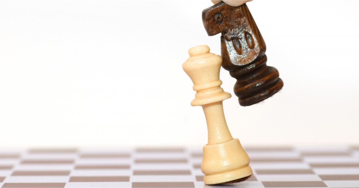 A black chess piece pushing off a white piece