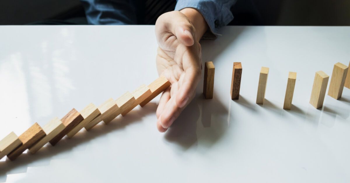 Person blocking a series of wooden blocks from falling over