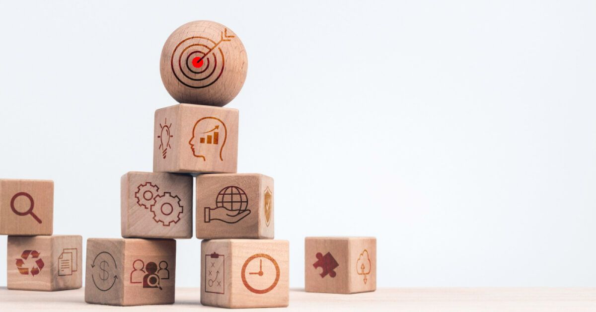 A stack of wooden blocks with various graphics, and a wooden sphere at the top of it