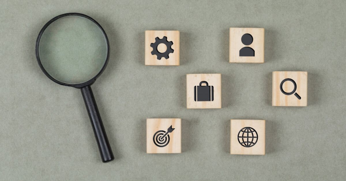 A magnifier glass placed next to a group of wooden blocks with graphics on them