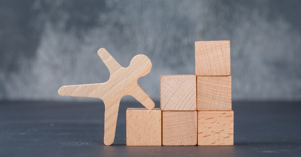 A wooden figurine next to stacked wooden blocks