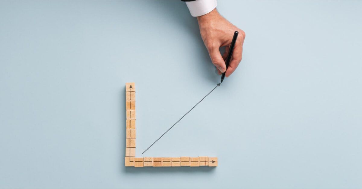 Person drawing an upward moving graph line within a wooden block graph