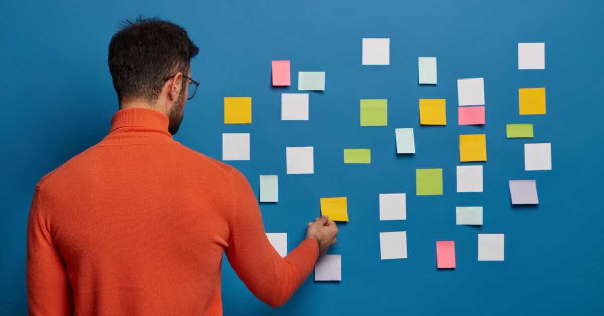 Person removing a note off a blue wall