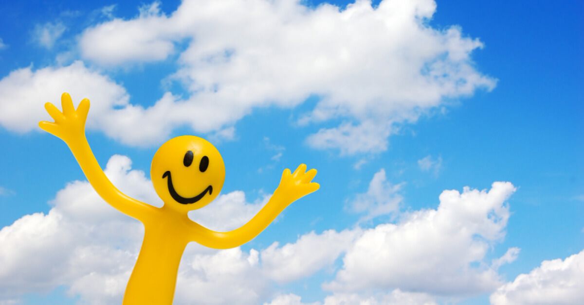 Yellow smiling figurine with a sky backdrop