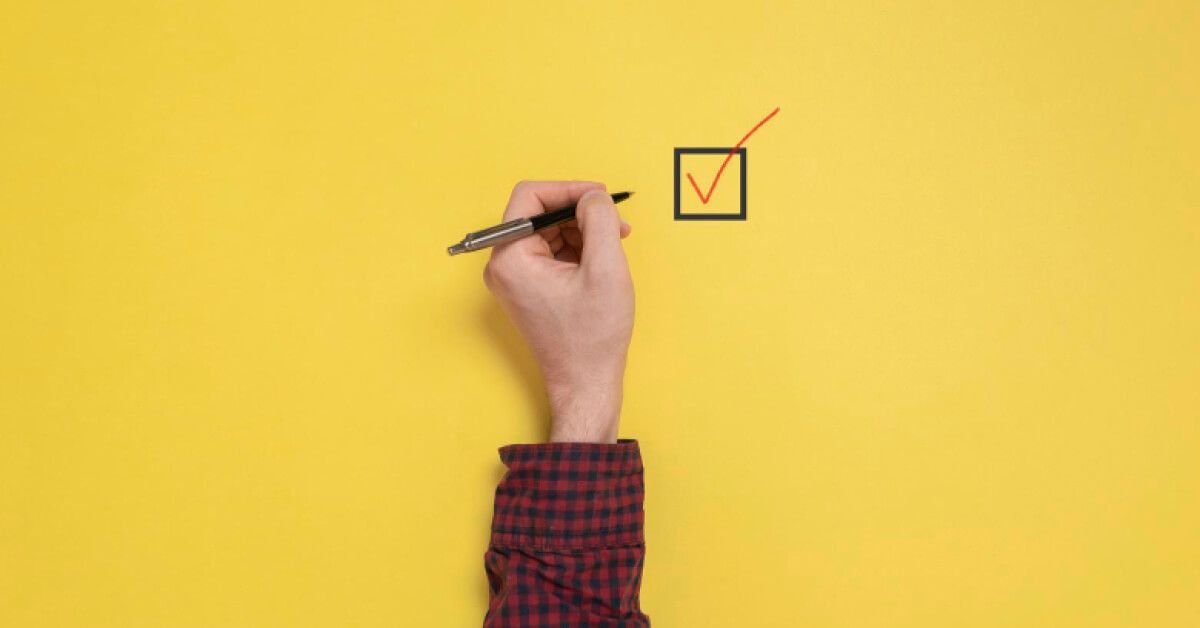 Person checking off a box against a yellow backdrop