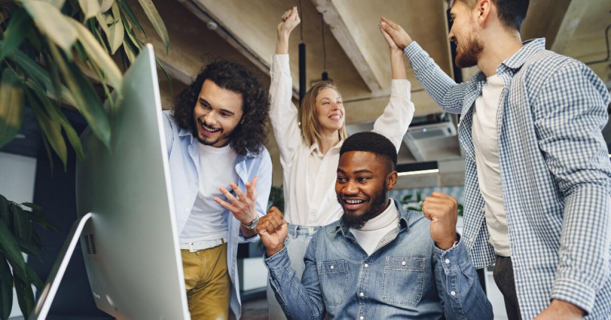 A group of excited employees in front of a desktop