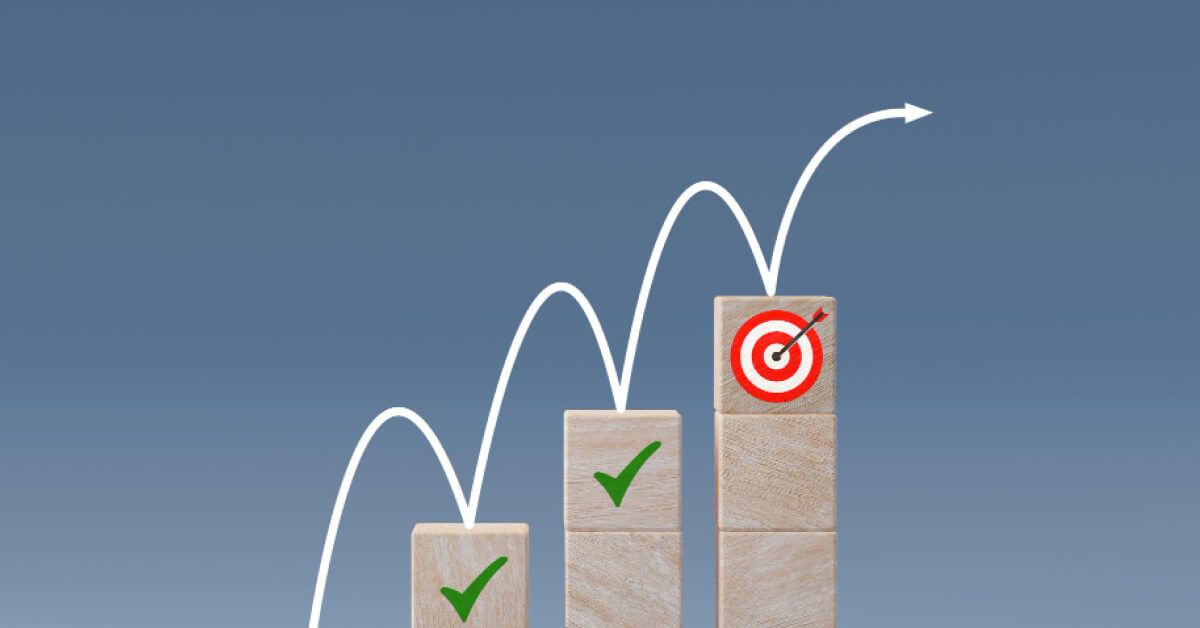 A looping arrow over an ascending series of wooden block towers with tick and target graphics