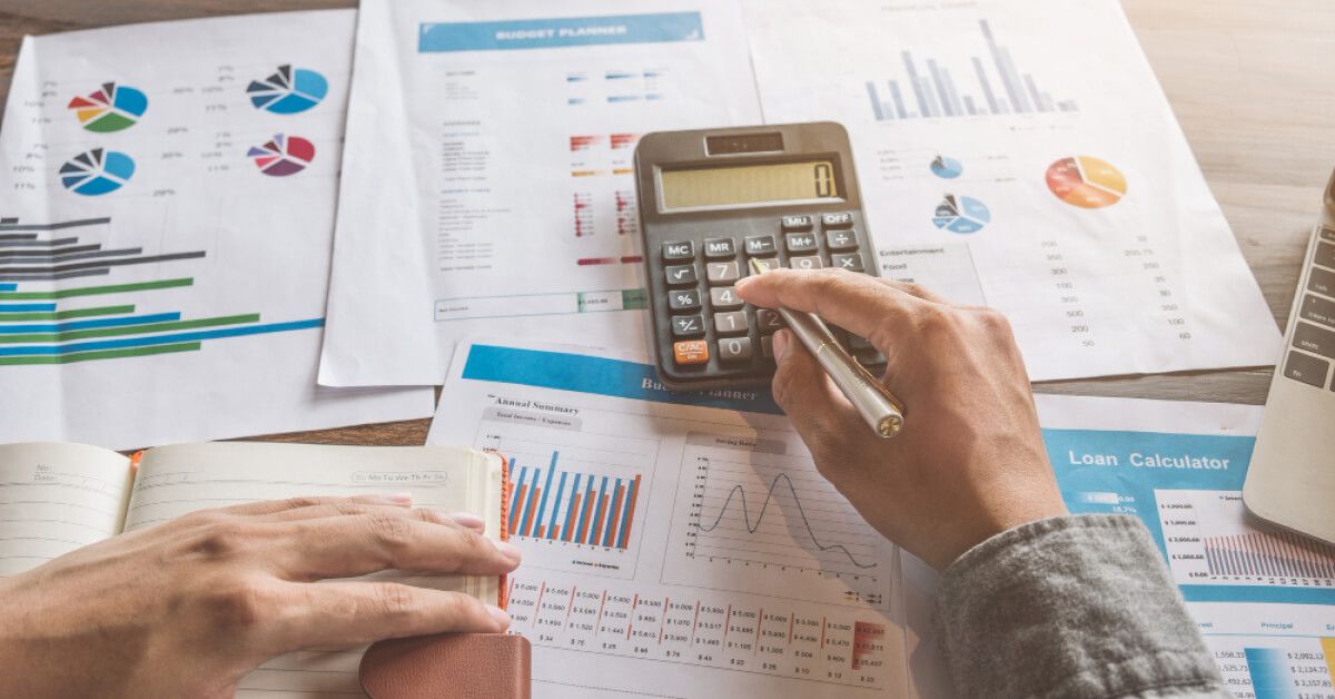 Person using a calculator amidst a set of data sheets