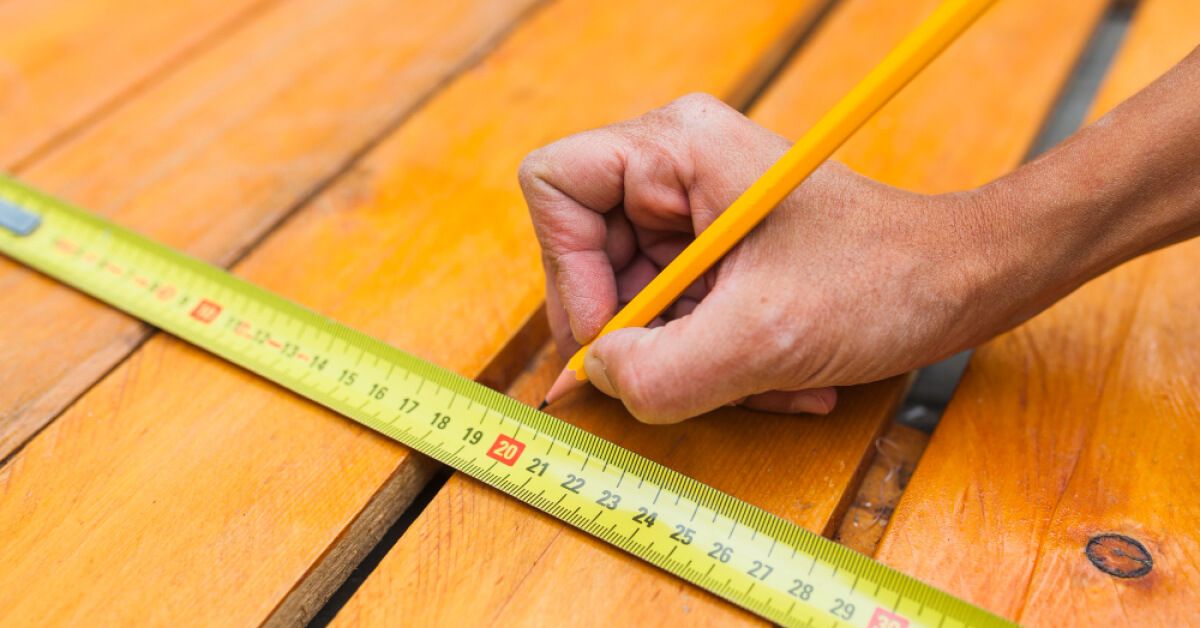 Someone using a tape measure and a pencil to mark a measurement