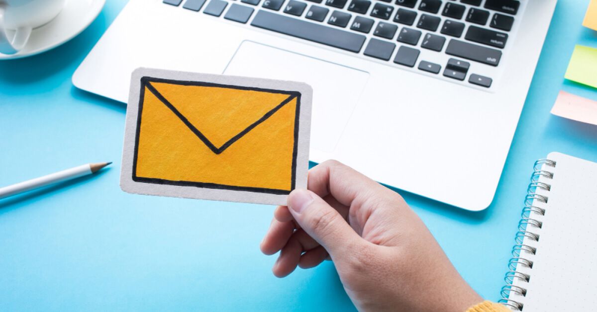 Employee holding an email cut out paper in their hand 