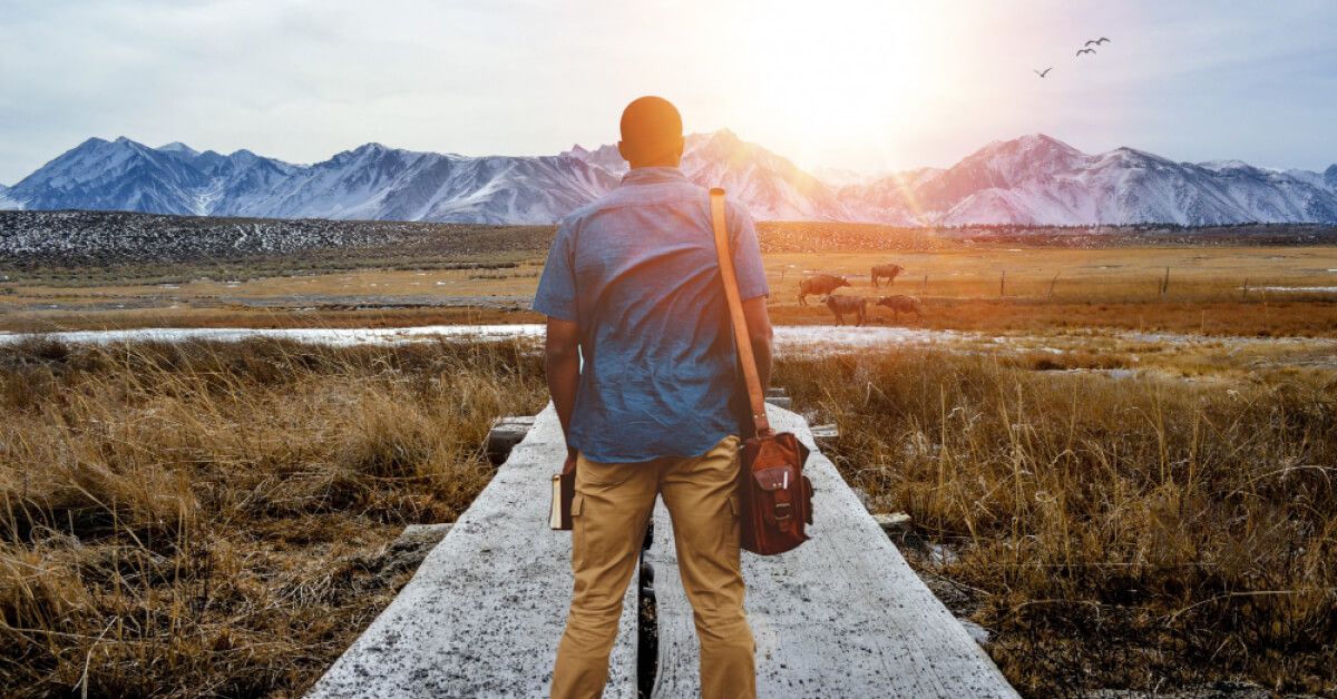 Person with a sling bag staring at a vast landscape