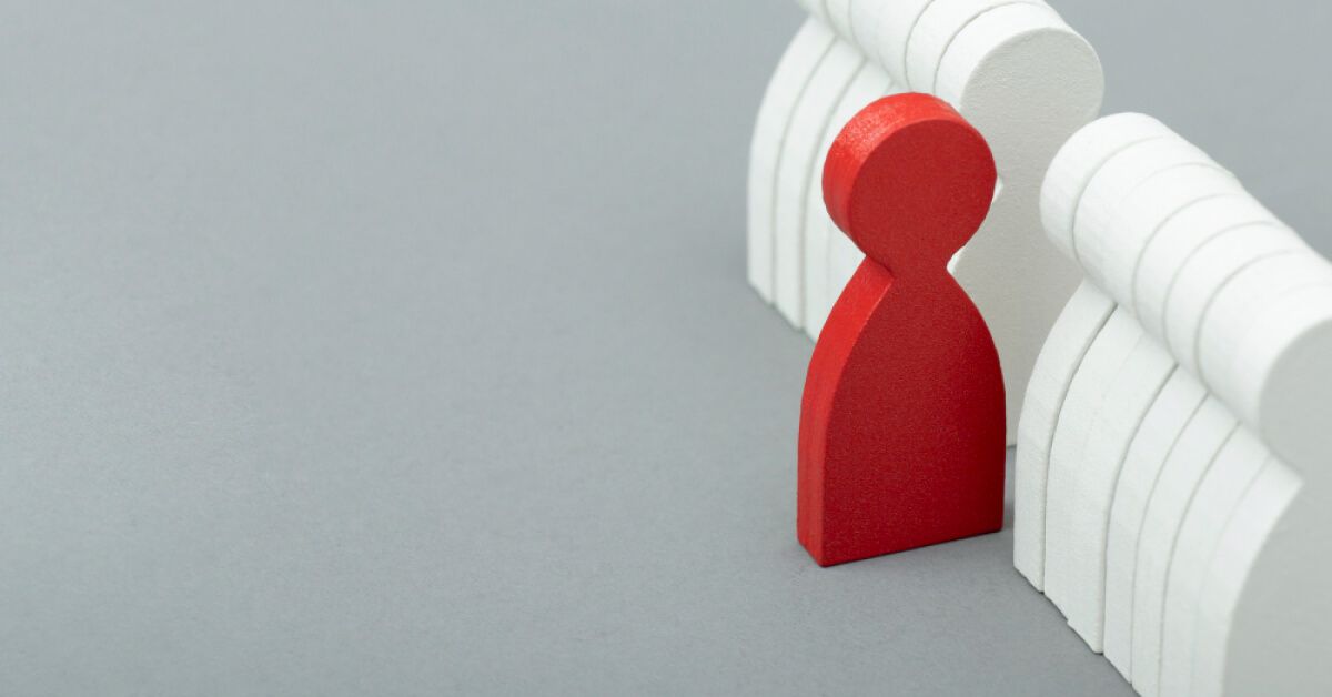 An odd red figurine standing out from a line of white figurines