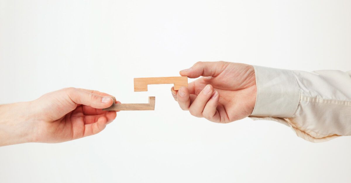 Two people joining interlocking wooden pieces