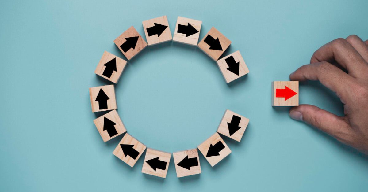 A circular arrangement of wooden blocks with black arrows, and a red arrow moving away from it