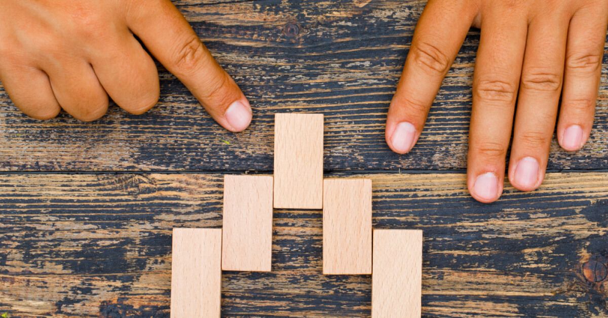 Person arranging a series of wooden blocks