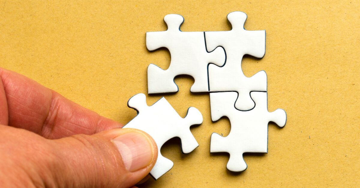 Person placing a puzzle piece into a puzzle