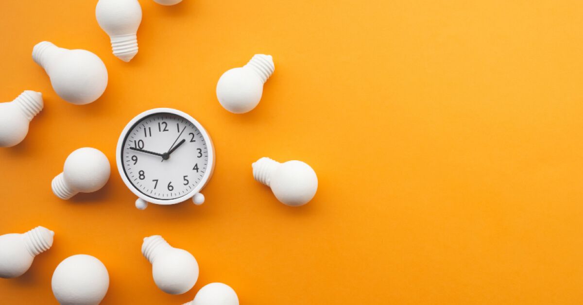 White lightbulbs around a clock, against an yellow backdrop