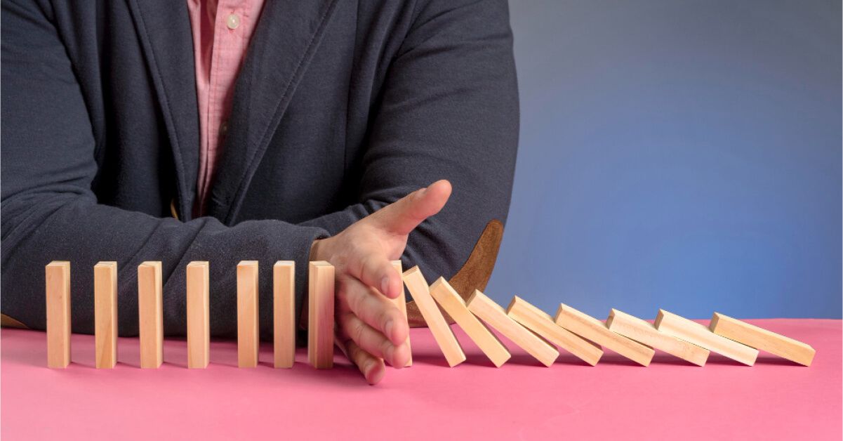 Person blocking a series of wooden blocks from falling over