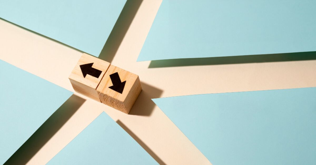 Two wooden blocks with arrows facing in different directions at a cross-path