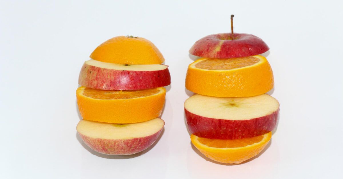 An apple and an orange cut into segments and mixed up next to each other